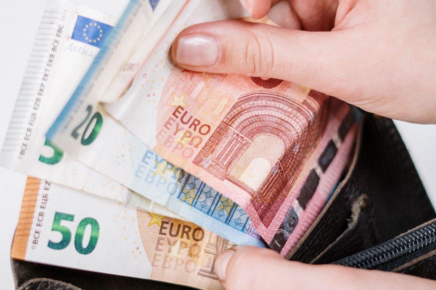 Hand nimmt Euro-Scheine aus einer Geldbörse